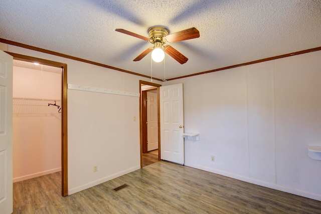 unfurnished bedroom with hardwood / wood-style flooring, ceiling fan, a textured ceiling, and crown molding