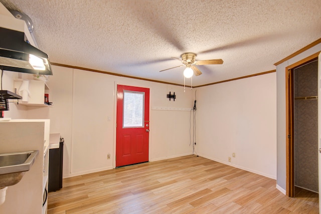 interior space featuring light wood-type flooring, a textured ceiling, ceiling fan, and crown molding