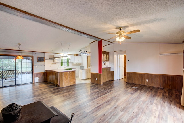 unfurnished living room with ceiling fan, a textured ceiling, hardwood / wood-style flooring, and ornamental molding