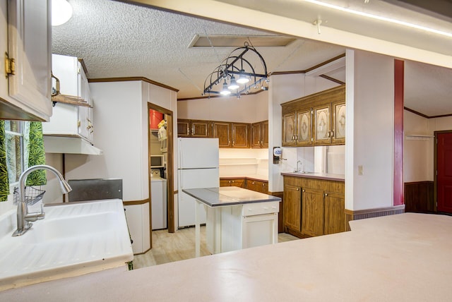 134 Old Spring Rd, Rising Fawn, GA 30738 - kitchen featuring freestanding refrigerator, a sink, washer / dryer, brown cabinetry, and a textured ceiling