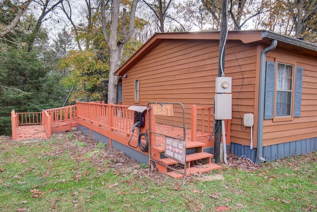 view of side of home with a deck and a lawn