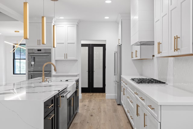 kitchen featuring light stone counters, appliances with stainless steel finishes, decorative light fixtures, and white cabinets