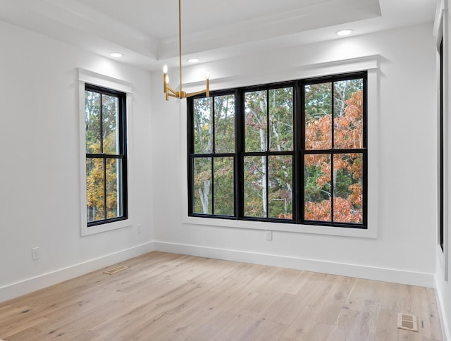 empty room featuring an inviting chandelier, light hardwood / wood-style flooring, and a healthy amount of sunlight