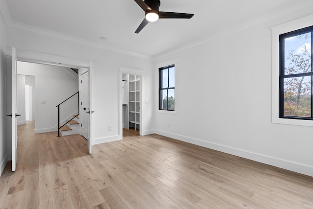 interior space with multiple windows, crown molding, light wood-type flooring, and ceiling fan