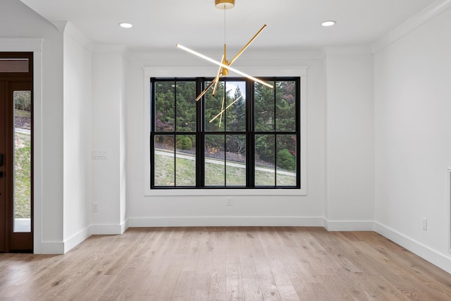 unfurnished dining area with light hardwood / wood-style flooring, ornamental molding, and a chandelier