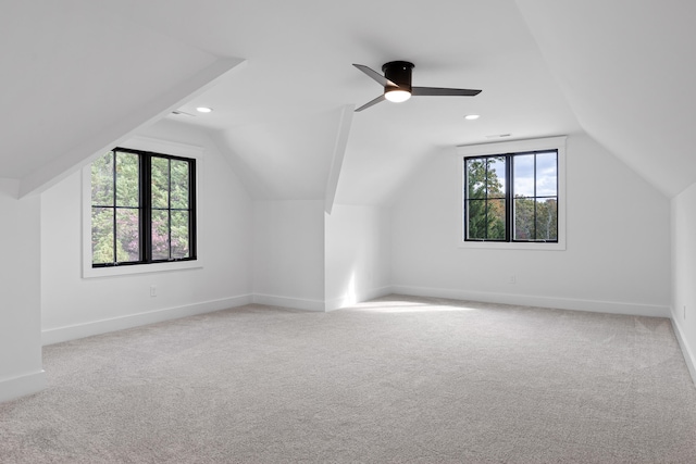 additional living space featuring lofted ceiling, light colored carpet, and a healthy amount of sunlight