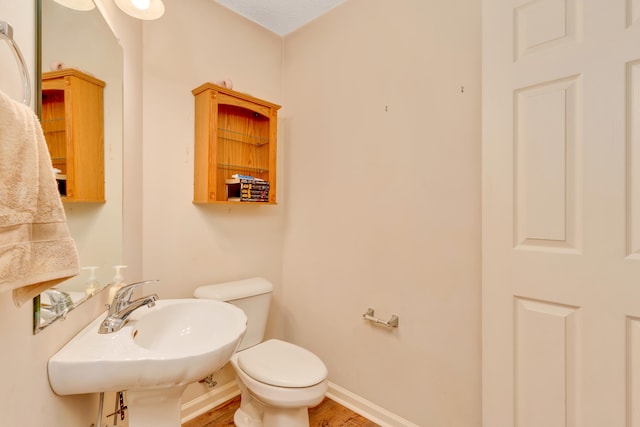 bathroom featuring toilet, sink, and hardwood / wood-style floors