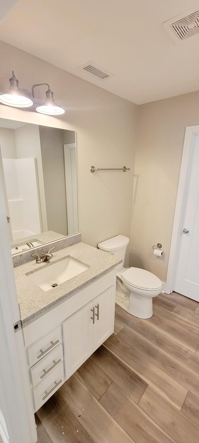 bathroom with vanity, toilet, and hardwood / wood-style flooring