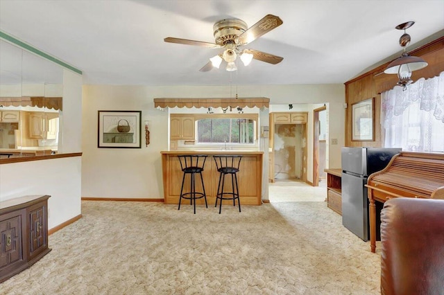 kitchen with light carpet, stainless steel refrigerator, hanging light fixtures, a kitchen breakfast bar, and ceiling fan