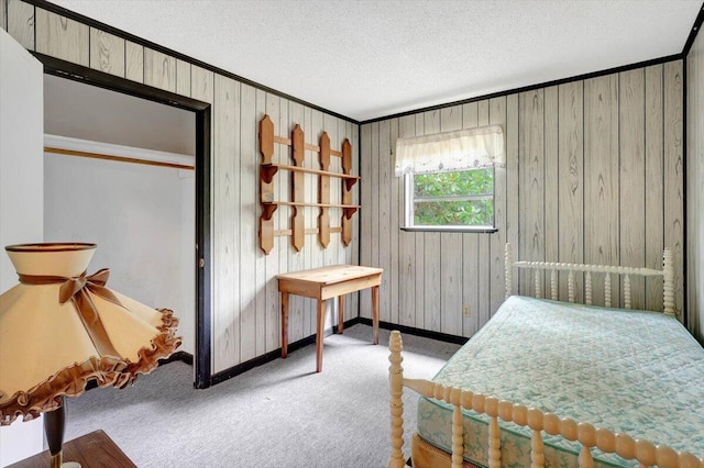 bedroom with wood walls, light colored carpet, and a textured ceiling