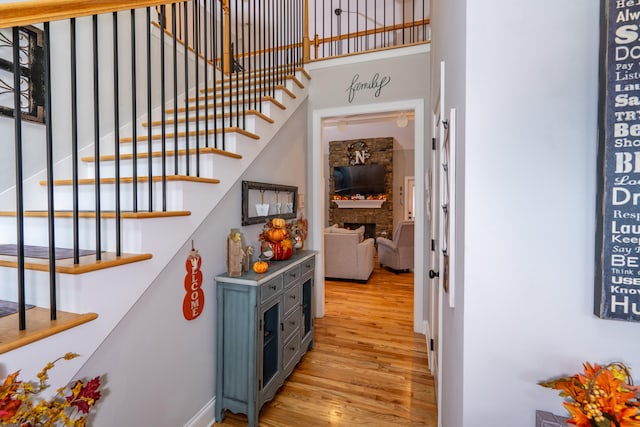 interior space featuring a stone fireplace, wood finished floors, and a high ceiling