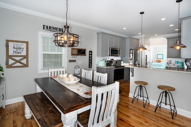 dining area with baseboards, ornamental molding, recessed lighting, and light wood-style floors