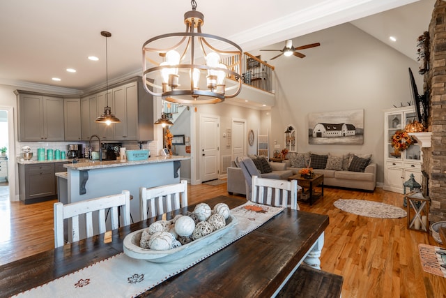 dining room with high vaulted ceiling, recessed lighting, light wood-style flooring, and ceiling fan with notable chandelier