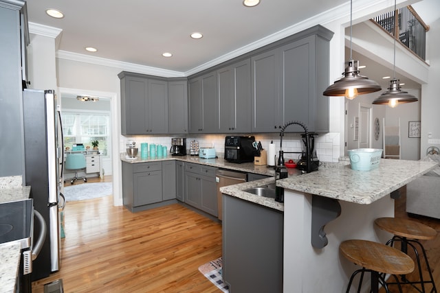 kitchen featuring a breakfast bar area, gray cabinets, ornamental molding, light wood-type flooring, and a peninsula