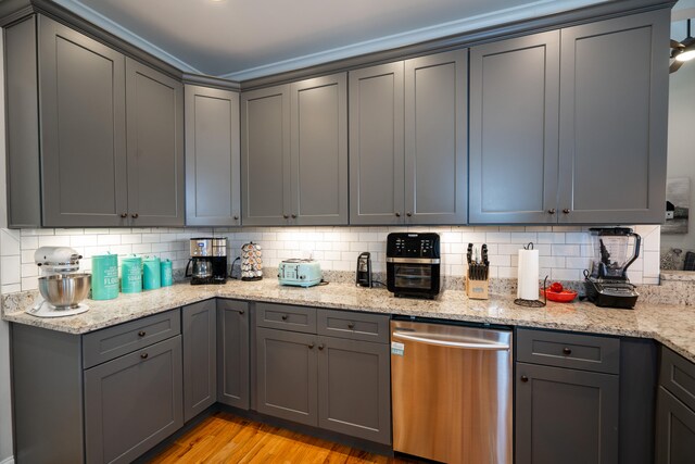 kitchen featuring light wood-style floors, gray cabinets, backsplash, and stainless steel dishwasher