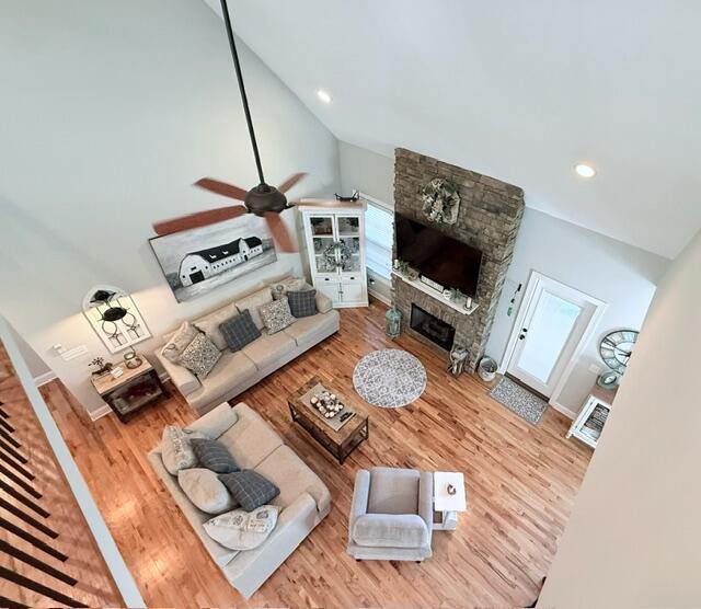 living area with a fireplace, recessed lighting, ceiling fan, vaulted ceiling, and wood finished floors