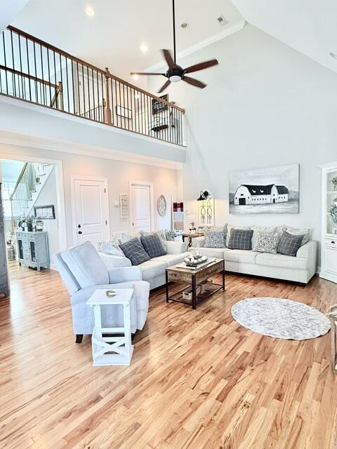 living area featuring ceiling fan, stairway, a towering ceiling, and wood finished floors