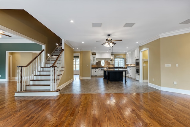 unfurnished living room featuring ceiling fan, dark hardwood / wood-style flooring, and ornamental molding