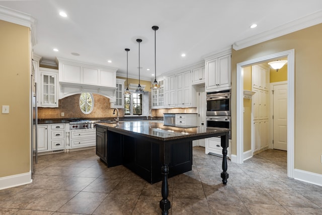 kitchen with a kitchen breakfast bar, hanging light fixtures, white cabinets, a large island, and decorative backsplash