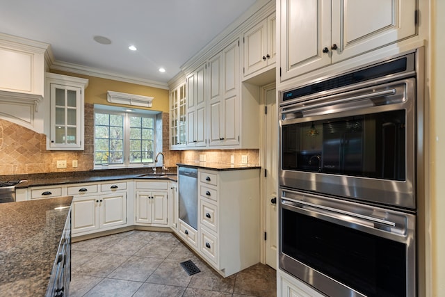 kitchen with sink, ornamental molding, dark stone countertops, light tile patterned floors, and backsplash