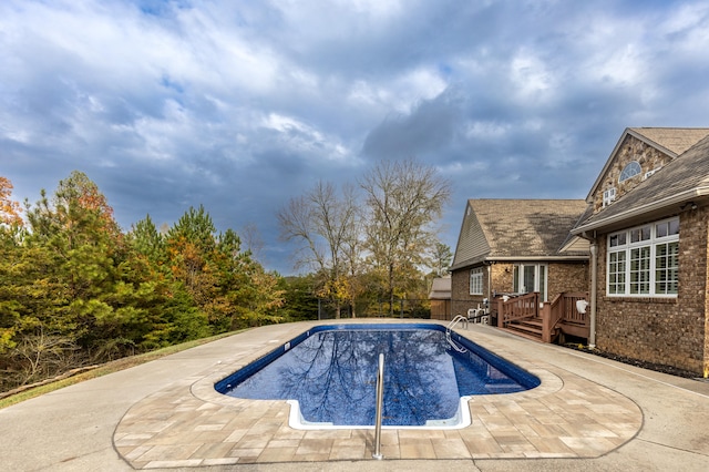 view of swimming pool featuring a wooden deck and a patio area