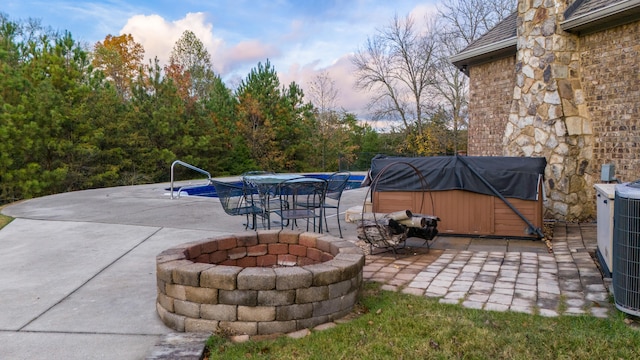 patio terrace at dusk with an outdoor fire pit and a hot tub