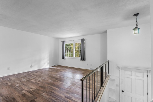 unfurnished room with dark hardwood / wood-style flooring and a textured ceiling