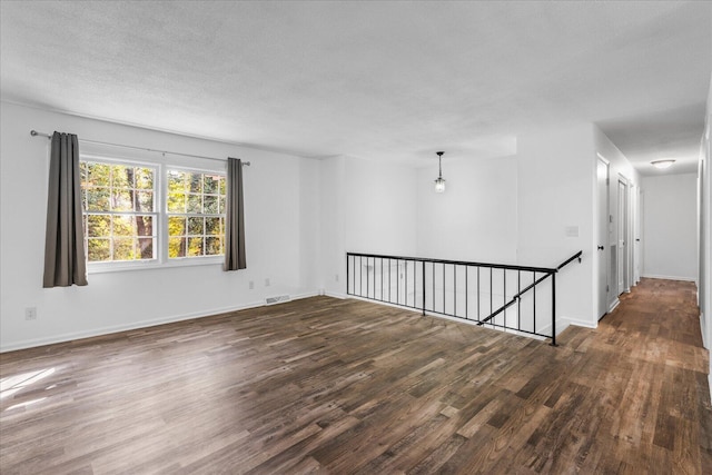 empty room featuring a textured ceiling and dark hardwood / wood-style floors