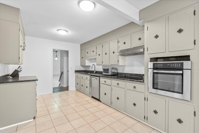 kitchen featuring a textured ceiling, appliances with stainless steel finishes, sink, and light tile patterned floors