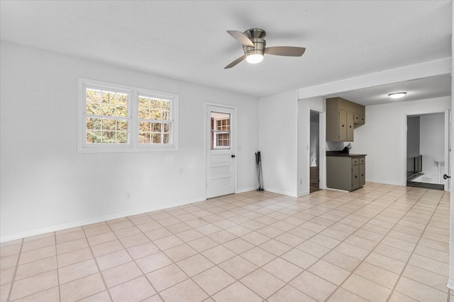 spare room with a textured ceiling, light tile patterned floors, and ceiling fan