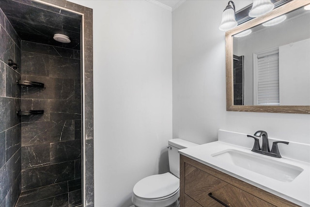 bathroom with vanity, toilet, tiled shower, and crown molding