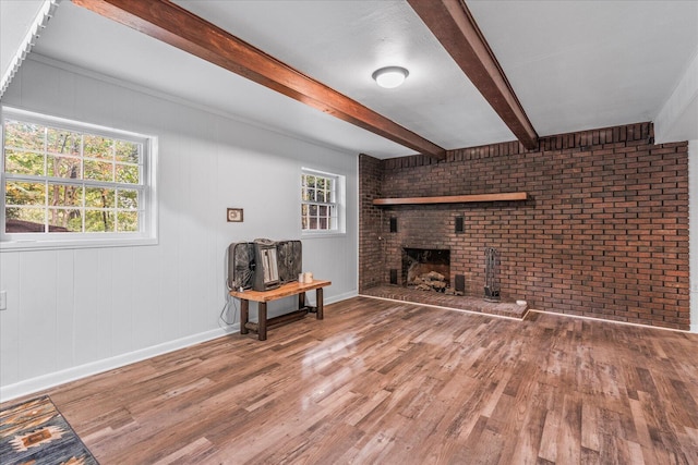 living room featuring hardwood / wood-style flooring, a brick fireplace, a healthy amount of sunlight, and beam ceiling