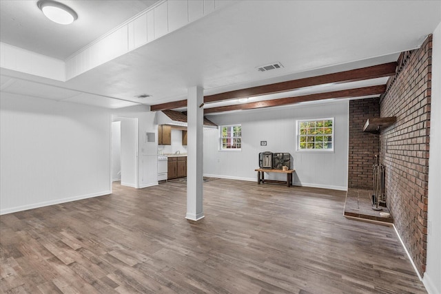 basement with hardwood / wood-style floors, a fireplace, brick wall, and sink