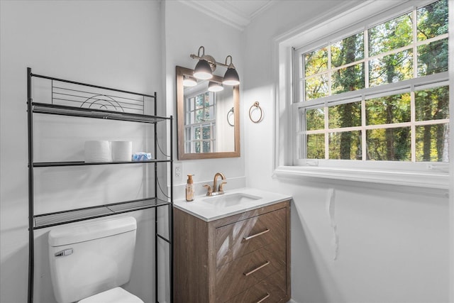 bathroom with toilet, vanity, and ornamental molding