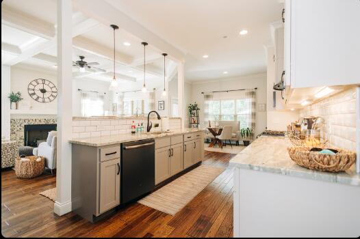 kitchen featuring sink, kitchen peninsula, light stone countertops, stainless steel dishwasher, and dark hardwood / wood-style flooring