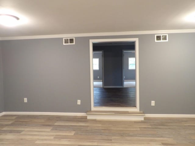 spare room featuring hardwood / wood-style floors and crown molding