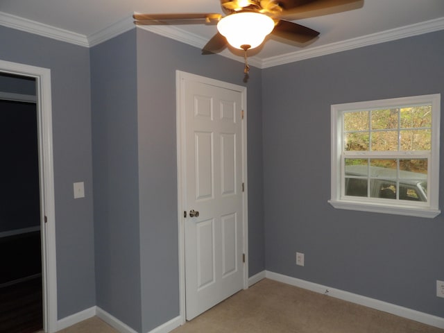 unfurnished bedroom with ceiling fan, light colored carpet, and crown molding