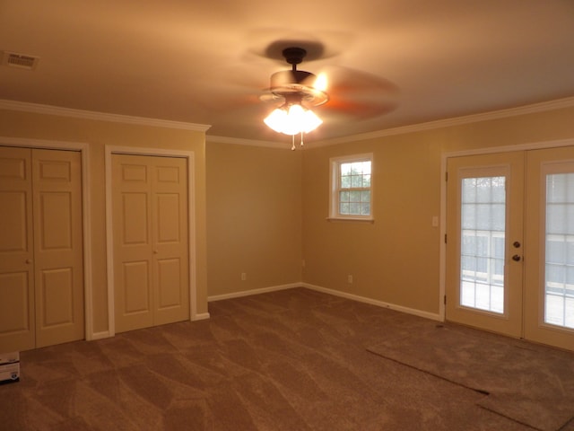 unfurnished bedroom with multiple closets, ceiling fan, french doors, dark colored carpet, and ornamental molding