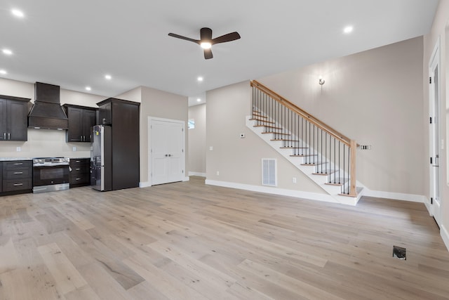 kitchen featuring light wood-type flooring, custom exhaust hood, ceiling fan, and stainless steel appliances