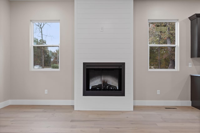 details with hardwood / wood-style flooring and a large fireplace