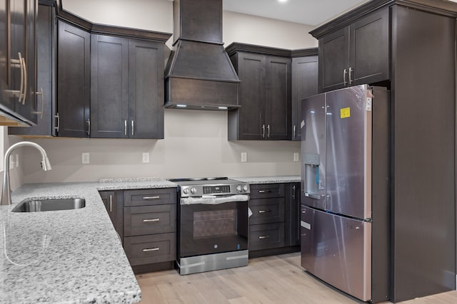 kitchen featuring light stone counters, appliances with stainless steel finishes, sink, custom exhaust hood, and light hardwood / wood-style flooring