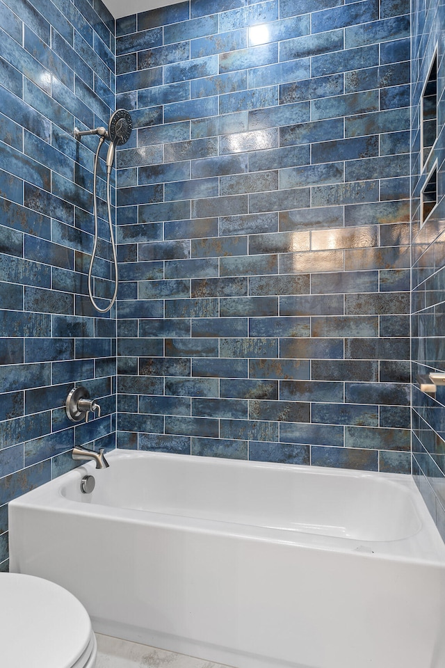 bathroom with tiled shower / bath and toilet