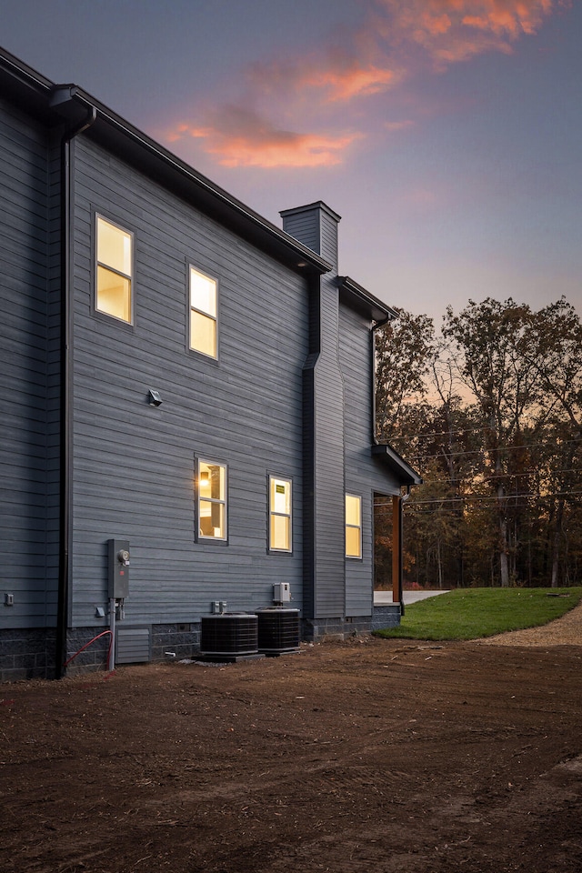 back house at dusk featuring central AC