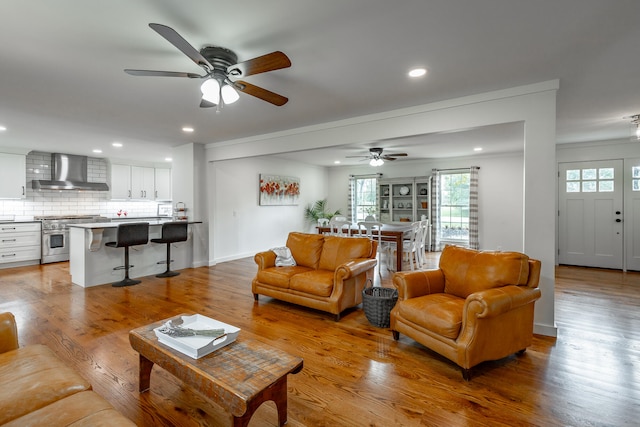 living room featuring ornamental molding, light hardwood / wood-style flooring, and ceiling fan