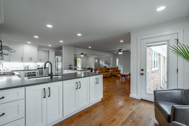 kitchen featuring light wood-type flooring, sink, a healthy amount of sunlight, and white cabinets