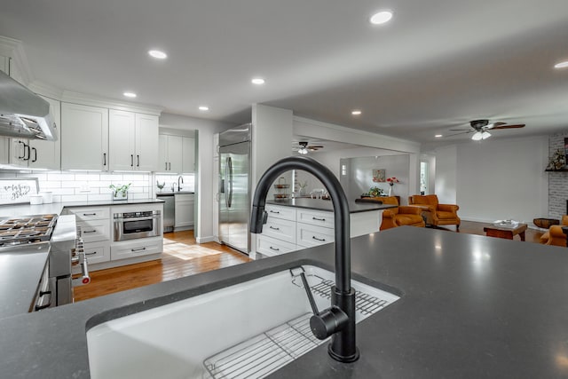 kitchen featuring white cabinets, light hardwood / wood-style floors, appliances with stainless steel finishes, and tasteful backsplash