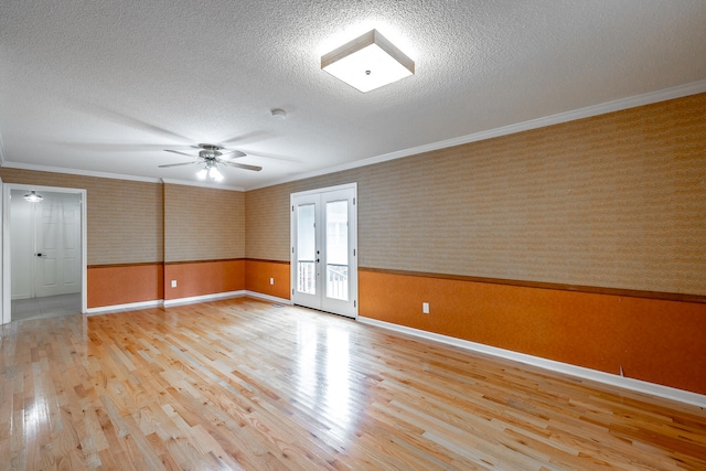 spare room featuring french doors, light hardwood / wood-style flooring, a textured ceiling, and crown molding