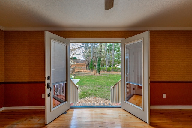 doorway to outside featuring ornamental molding, ceiling fan, a textured ceiling, light wood-type flooring, and french doors