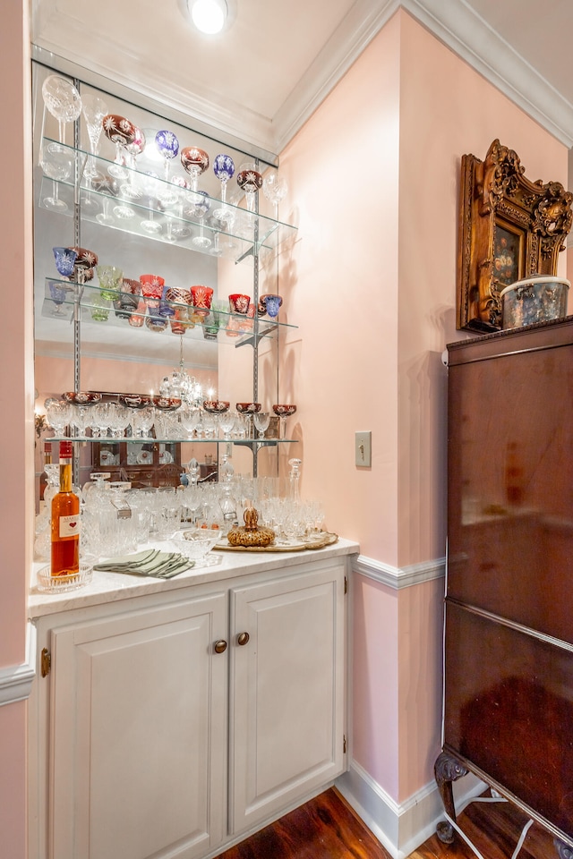 bar with dark hardwood / wood-style flooring, white cabinetry, and crown molding