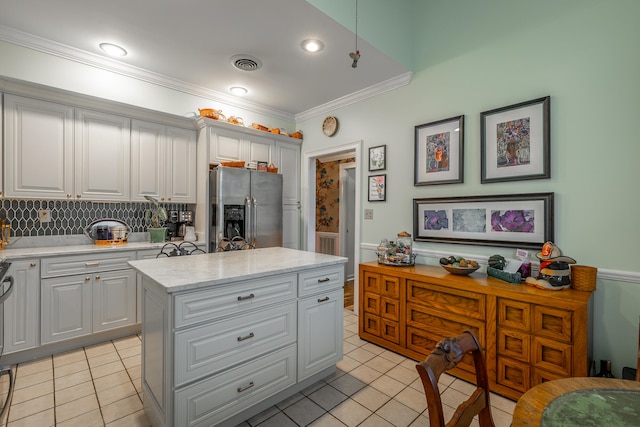 kitchen with decorative backsplash, a center island, stainless steel fridge with ice dispenser, and white cabinets